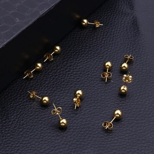 Polished 18k gold plated stainless steel ball stud earrings on black leather background