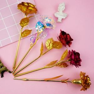 Colorful artificial foil roses in gold and red with an Eiffel Tower model on pink background