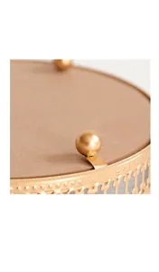 Detail of gold metal hollow pattern and spherical support feet on mirror tray