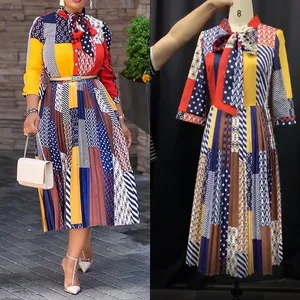 Detail of multi-color pleated dress with bow tie neck, long sleeves and belted waistline