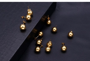 Detailed macro of 18k gold plated stainless steel ball stud earrings on black leather
