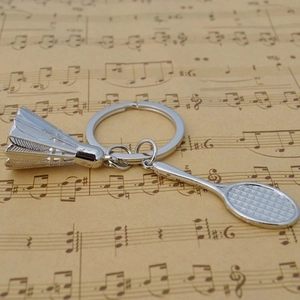 Detail view of silver metal badminton racket and birdie keychain on vintage paper