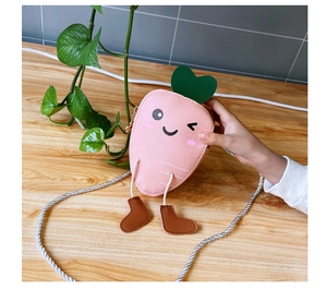 Detail of pink carrot-shaped kids purse with cartoon expression and cute small boot charms
