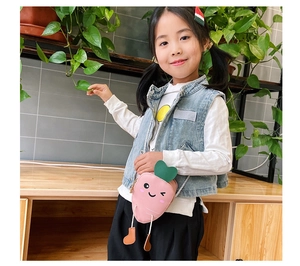Pink carrot cartoon crossbody bag for kids with green leaf detail worn by a child model