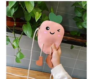 Detail of pink carrot-shaped kid cross-body bag with cute leaf and feet charms