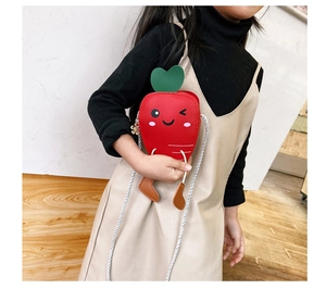 Detail view of the red carrot-shaped kids bag featuring green leaf and stitch textures