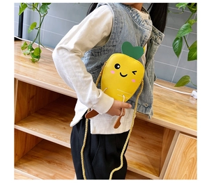 Kid modeling a yellow carrot shaped cartoon crossbody bag with thin shoulder strap