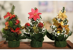 Three mini Christmas trees with bows and floral ornaments on a rustic wooden table