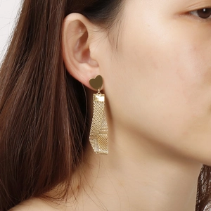 Golden heart stud earrings with twisted mesh chain tassel on a female model