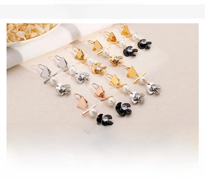 Detailansicht goldener, stählerner und roségoldener Perlenohrringe mit Muschelblumenakzenten