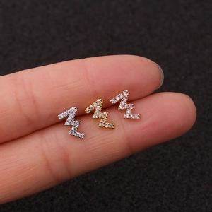Macro shot of three lightning bolt stud earrings with cubic zirconia in silver and gold