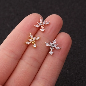 Macro shot of stainless steel cartilage studs with zircon crosses and flower designs