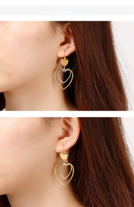 Detail view of layered gold and silver heart-shaped drop earrings worn by a model