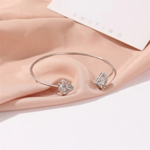 Détail d'un bracelet triangle évidé en argent avec zircon sur un tissu en soie rose