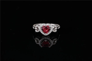 Macro shot of a silver heart ring with a vibrant red gemstone and sparkling halo detail