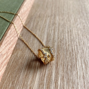 Detailed close-up of 925 silver golden necklace with pave zircon cylinder pendant