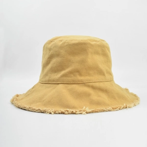 Close-up of mustard yellow bucket hat featuring frayed edges and vintage canvas texture