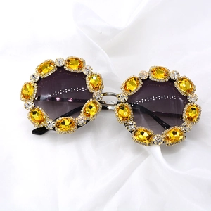 Close-up of oversized black sunglasses with yellow rhinestones and white crystals