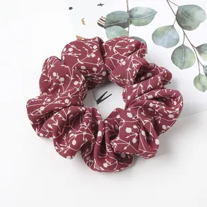 Close-up of wine red floral scrunchie with soft fabric texture and leaf patterns