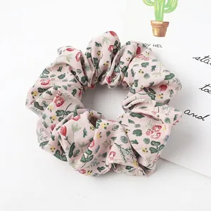 Detail of pink floral fabric scrunchie with soft ruffled texture on white backdrop