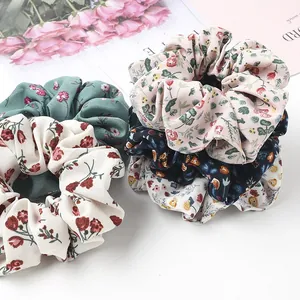 Close-up of four floral print hair scrunchies in assorted colors with ruffled fabric details