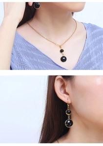 Detail of elegant gold necklace and earrings set featuring faceted black round gemstones
