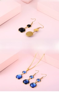 Detail of elegant gold earrings and necklace set with black and blue round gemstones