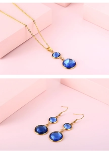 Detail of gold-tone necklace and earrings set with faceted blue gems on pink display