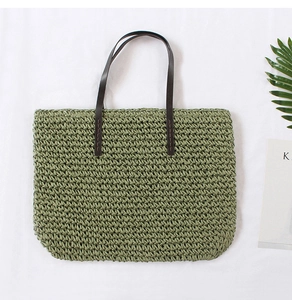 Detail of sage green straw tote bag showing hand-woven texture and brown leather handles
