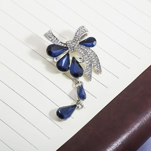 Détails de la broche nœud argentée avec cristaux bleu foncé et pendentifs pendants