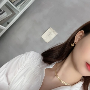 Close-up of a model wearing a gold leaf texture necklace and heart-shaped earrings