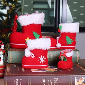 Close-up of red flocked Christmas boots with tree and bell details on vintage books