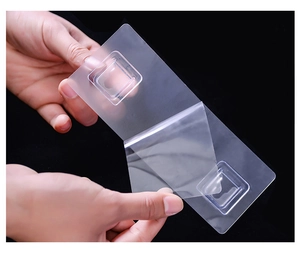 Detail showing hands peeling protective film from transparent double adhesive wall hook