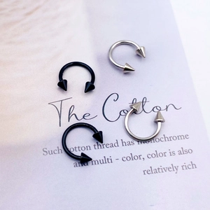 Macro view of black and silver stainless steel CBR horseshoe piercings with pointed cones