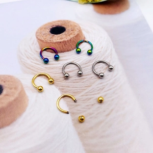 Macro shot of U-shaped nose and lip rings in colorful, silver and gold finishes