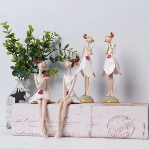 Detailed view of four resin ballet dancer figurines in floral white dresses on book props