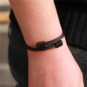 Detailopname van een zwarte gedraaide roestvrijstalen armband met vierkante metalen kappen