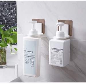 Detail of white wall-mounted shampoo holders on marble tiles with strong adhesive