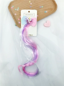 Detail of glitter unicorn bow hairclip with long colorful gradient curly wig for kids