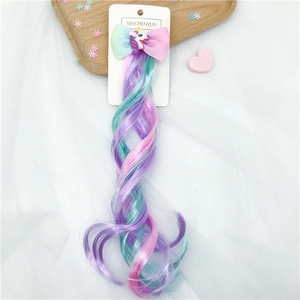 Detail of rainbow unicorn hair extension with gradient bow and glittery horn on white fabric