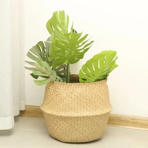 Detail of handwoven seagrass plant basket featuring sturdy handles and Monstera leaf decor