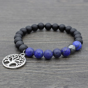Detail of beaded bracelet featuring matte black beads and silver tree of life charm