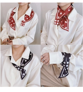 Dettaglio di foulard in seta a pois rosso e nero indossato come sciarpa e nastro da polso