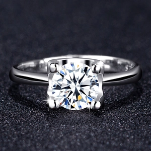 Macro shot of silver four-prong solitaire ring with brilliant round cut zircon on textured surface