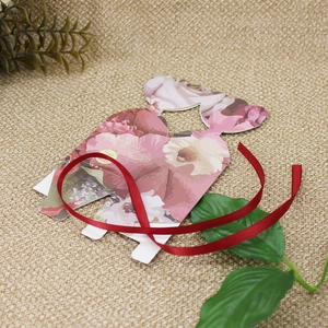 Detail of wedding favor box with pink floral patterns and red ribbon on burlap