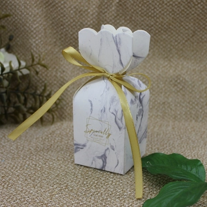 Close-up of marble pattern gift box with petal top and elegant gold ribbon bow