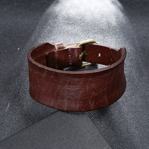 Detail view of a wide dark brown leather bracelet with vintage bronze buckle