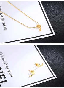 Detailed view of golden dolphin pendant necklace and matching stud earrings set