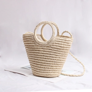 Detail of beige straw handbag with circular handles and woven texture on a magazine