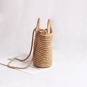 Handwoven beige straw bucket bag with round handles and strap for summer beach vacation